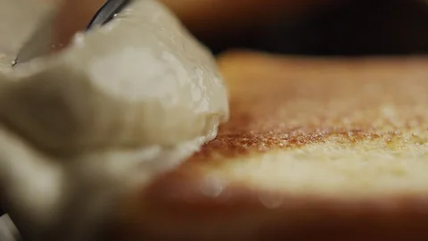 Macro shot of man with knife spreading cream cheese on toast. Slow motion video Stock Footage 116311260