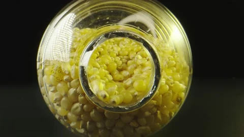 Macro shot moving to the inside of a jar filled with popcorn seeds Stock Footage 131689457