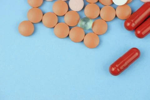 Macro shot of multi-colored pills and capsules heap on a blue background Stock Photos