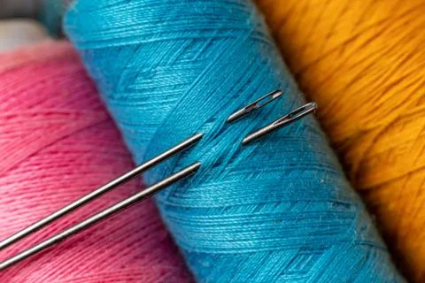 Macro shot of needle inserted in the color thread rolls Foto stock