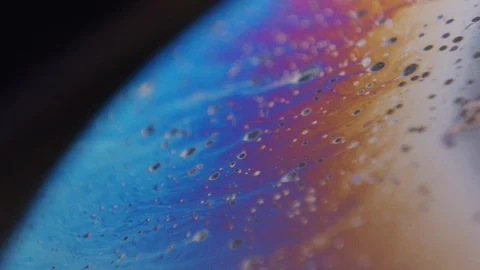 Macro shot of oil moving on a soap bubble. Small particles moving with the Stock Footage 128980433