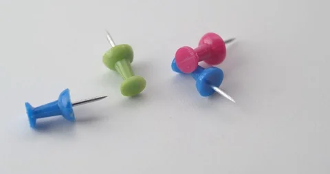 Macro shot of push pins dropping onto a white surface Stock Footage 117350083