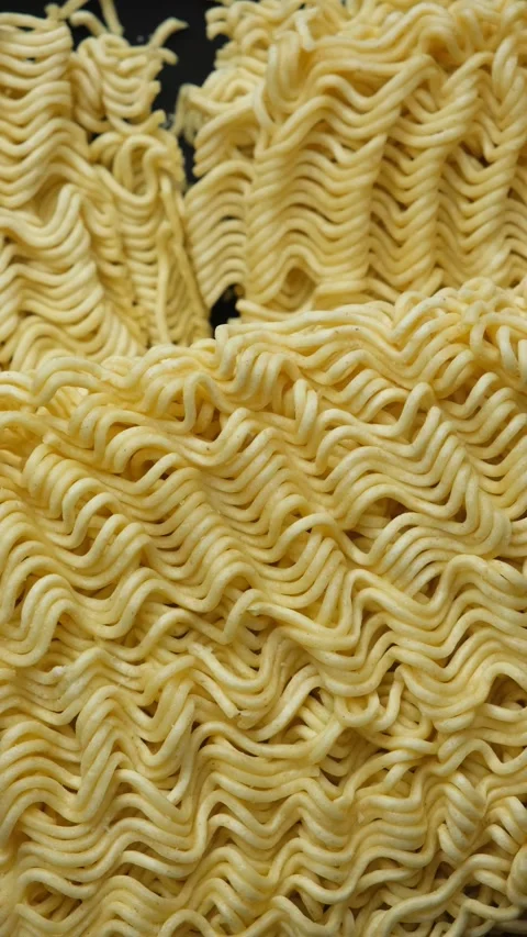 Macro shot of raw instant ramen noodle blocks slowly rotating in vertical view Stock Footage 346687743
