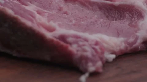 Macro shot of raw pork chop on wooden table Stock Footage 138301119