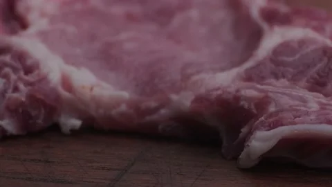 Macro shot of raw pork chop on wooden table. Stock Footage 138302924