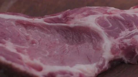 Macro shot of raw pork chop on wooden table. Stock Footage 138302961