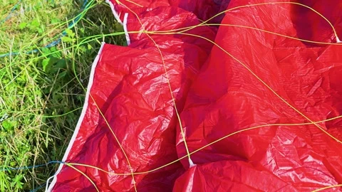 Macro shot of a red parachute canopy with thin green and blue lines on grass Stock Footage 337504845