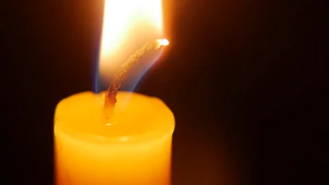 A macro shot reveals the bright wick of the candle as soft flicker shapes a deep Stock Footage 323352285