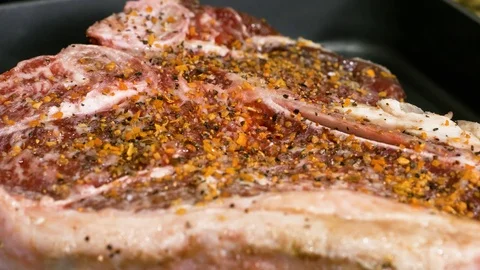 Macro shot of roasting piece of meat with seasonings on the hot pan Stockbeeldmateriaal 102611795