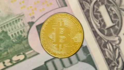 Macro shot of a rotating bitcoin against the background of dollar bills. Crypto  Stock Footage 198183882