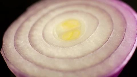 A macro shot of a rotating slice of a sliced ​​ripe purple onion Stock Footage 235556889