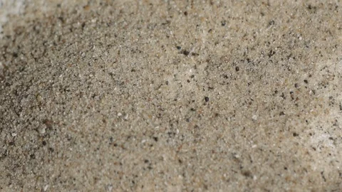 Macro shot of sanding being blown away off of a white backdrop Stock Footage 88049119