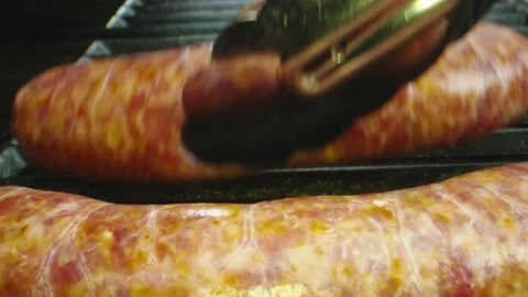 Macro shot of sausages being put on bbq grill Stock Footage 131691031