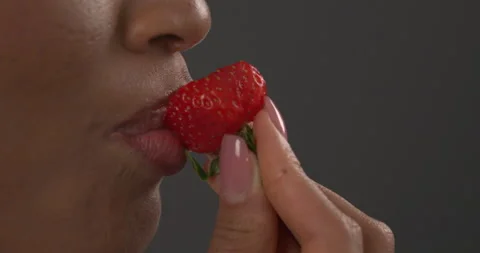 Macro shot side view of African female's mouth eating juicy strawberry. Sensual Stock Footage 154738127