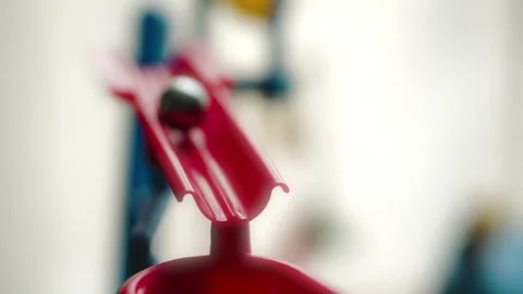 Macro shot of a silver, metallic marble ball rolling down a red plastic slide Vídeos de archivo 328125740
