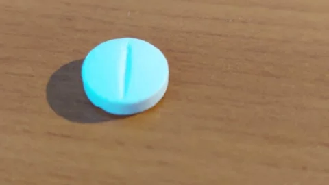 Macro shot of a single light blue round pill on a wooden background Vídeos de archivo 333641517