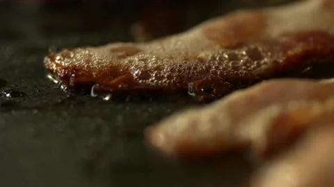 Macro shot of sizzling bacon while being fried. Cooking bacon, closeup view. 스톡 동영상 334641905
