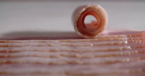 Macro shot of the slice of bacon is rolled up by finger. Dishes with bacon and Stock Footage 168572899