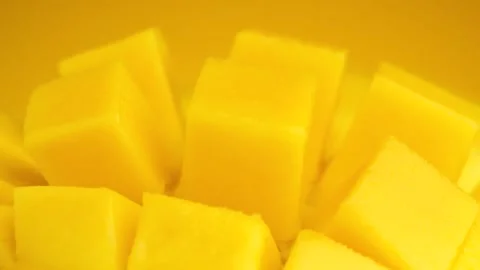 Macro shot Slice mango cubes rotating against Yellow background, Tropical Video stock 200663125