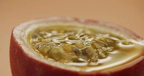 Macro shot of sliced fresh exotic passion fruit with pulp spinning on table Stock Footage 125421038
