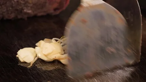 Macro Shot of Sliced Garlic Sautéing on a Professional Flat Top Grill Stock Footage 333520358