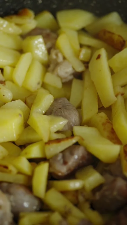Macro shot of sliced potatoes and meat frying in pan Stock Footage 337046725