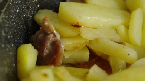 Macro shot of sliced potatoes and meat frying in pan Stock Footage 337046734