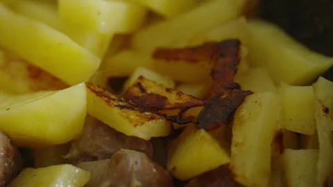 Macro shot of sliced potatoes and meat frying in pan Stock Footage 337046747