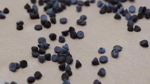 Macro Shot of Small Dark Chocolate Drops Scattered on a Sandy Surface Stock Footage 331780021