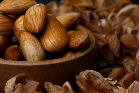 Macro shot of Soaked almonds in a rustic wooden bowl surrounded by peeled a.. 스톡 사진