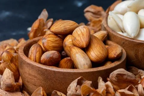 Macro shot of Soaked almonds in a rustic wooden bowl surrounded by peeled a.. Stock-Fotos
