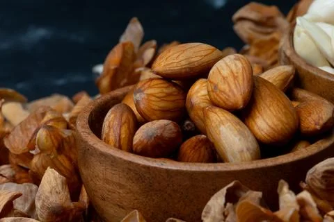 Macro shot of Soaked almonds in a rustic wooden bowl surrounded by peeled a.. 스톡 사진