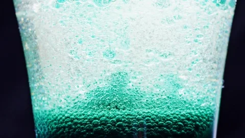 Macro shot of sparkling blue bubbles moving up in a glass with bright Video stock 124671040