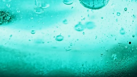 Macro shot of sparkling blue bubbles falling to ground in bright blue water Video stock 124671112