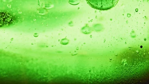 Macro shot of sparkling green bubbles falling to ground in bright green Video stock 124671123
