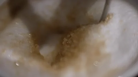 Macro shot of spoon stirring a cup of cappuccino coffee with suigar and foam  Stock Footage 330099339