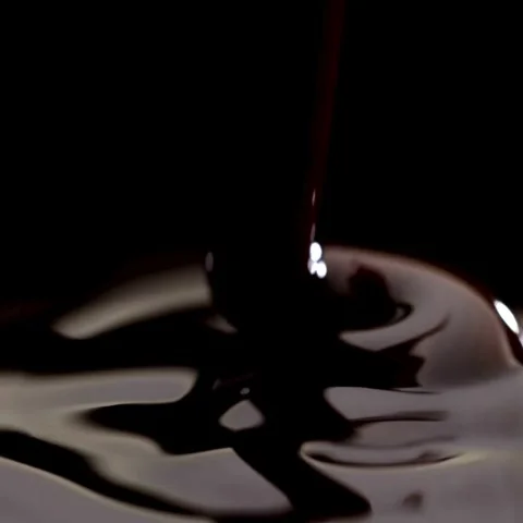 Macro Shot of Thick Dark Melted Chocolate or Syrup Pouring and Pooling on Black Stock Footage 322523884