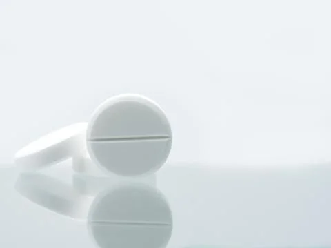 Macro shot of three white chewable tablets on white background with shadows.  Stock-Fotos