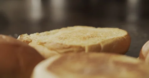 Macro shot of tweezers chef puts piece of butter on bun to burger. Slow motion Stock Footage 116244582