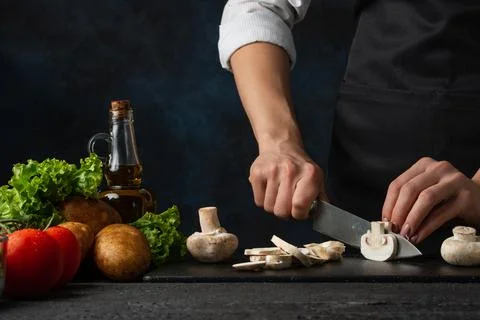 Macro shot view of chef in black apron cuts with knife mushrooms on the chopp Stock Photos