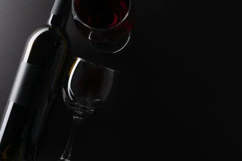 Macro shot view of elegant dark bottle and glasses with remains of red wine o Stock Photos