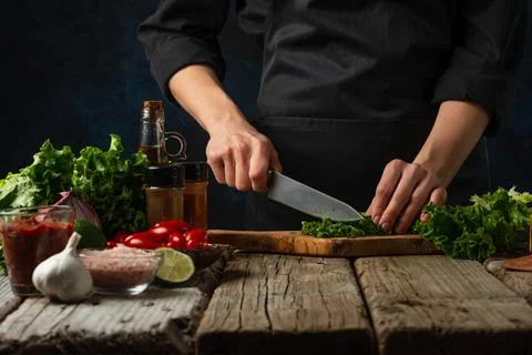 Macro shot view of professional chef in black uniform cuts with knife parsley Foto stock