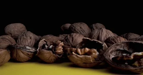 Macro Shot of Walnuts which lie on a yellow table against a black background Stock Footage 157519479