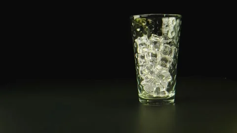 Macro shot of water being poured on a glass with ice, black background. Stock Footage 131690860