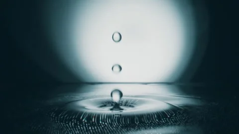 Macro shot of water drop falls down on grey transparent fluid surface creatin 库存影片 330112658