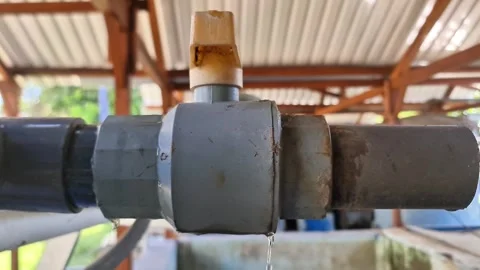 Macro Shot of a Weathered PVC Pipe Fitting Dripping Water in Industrial Setting Stock-Footage 337723055