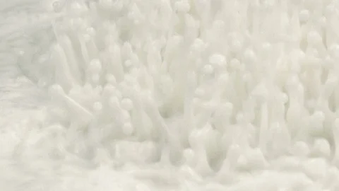 Macro shot of white fluid creating drops and splashes caused by sound vibrations 库存影片 98635742