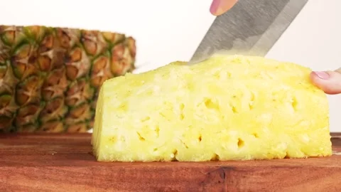 Macro shot of a woman using a knife to cut pineapple slices. Ideal for food.. Video stock 314431330