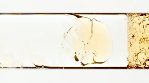 Macro Shot of Yellow Air Bubbles on White Background. Liquid Gold Oil Gel Stock Footage 196821661