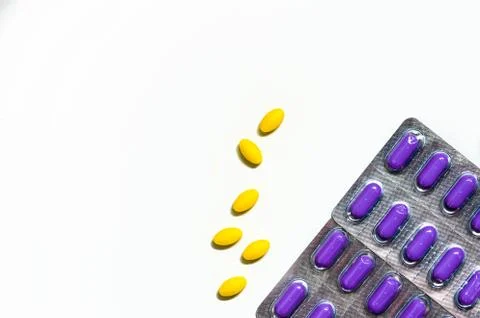 Macro shot of yellow oval tablet pills on white background and purple caplets Foto stock